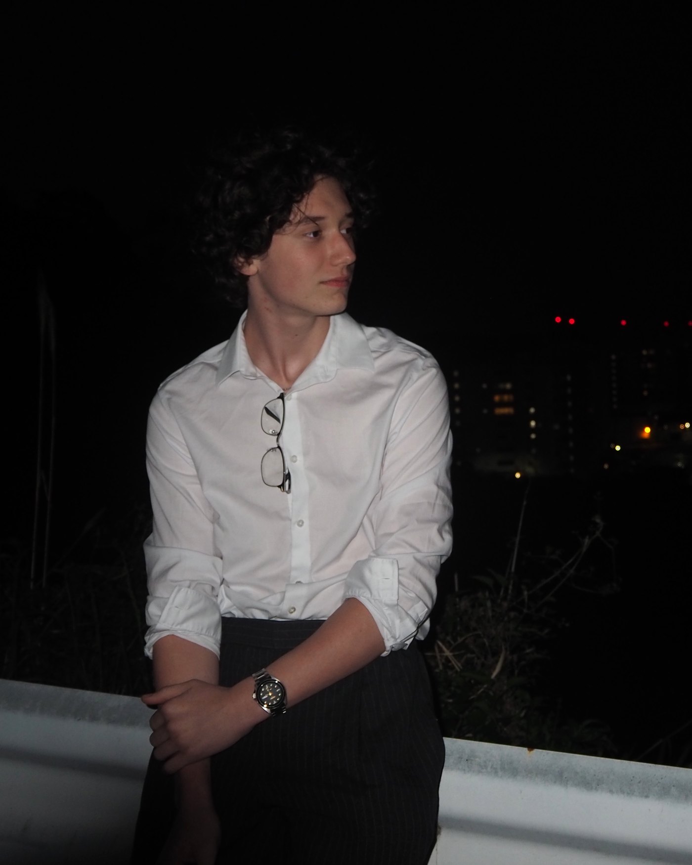 Ian in a white shirt at night with city lights behind him